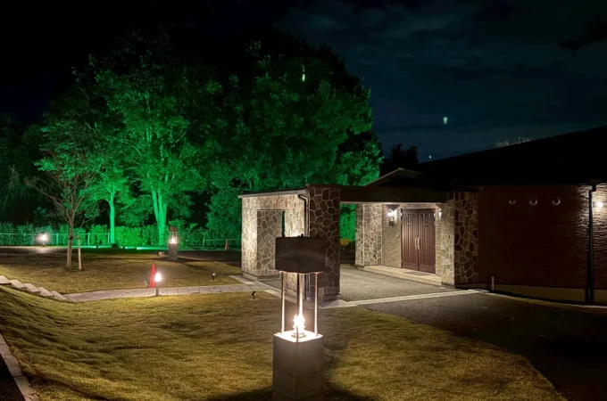 緑のライトで樹木を照らした夜の庭園と石造りの建物の外観