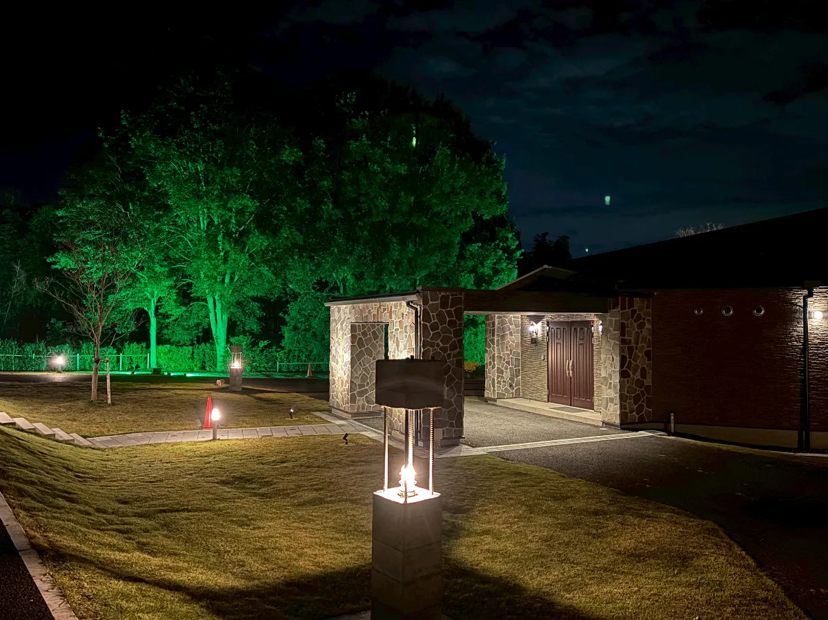 緑のライトで樹木を照らした夜の庭園と石造りの建物の外観
