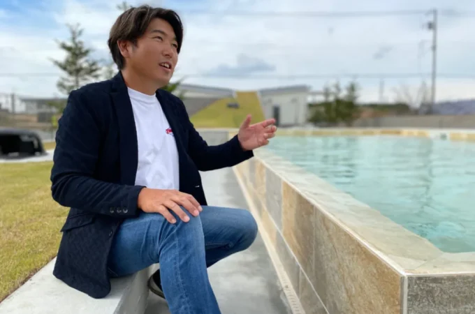 プールサイドに座る田村大氏（ドリームガーデン代表取締役・FINEGLAMPING CEO）