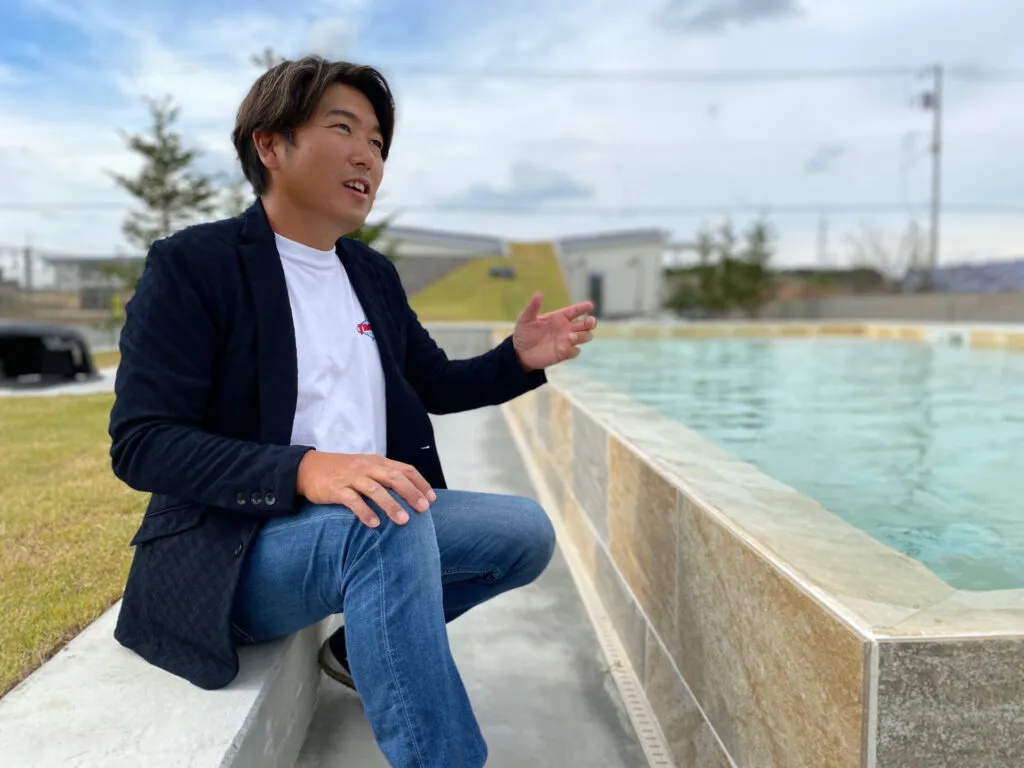 プールサイドに座る田村大氏（ドリームガーデン代表取締役・FINEGLAMPING CEO）