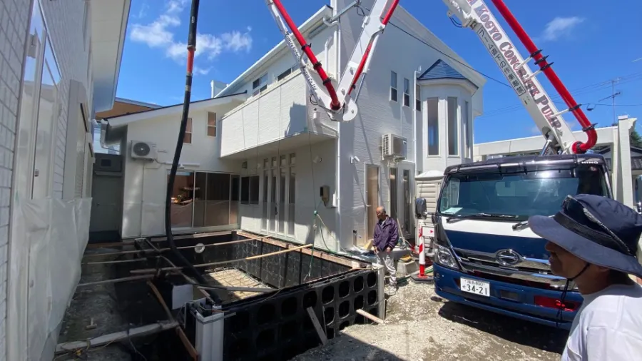 「コンクリートポンプ車でプールの躯体を施工する現場」