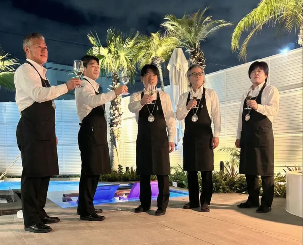 夜のプールサイドでプールソムリエ5名が乾杯している様子
